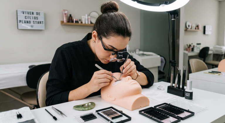 Jovem mulher concentrada praticando aplicação de extensões de cílios com kit profissional em um ambiente de aprendizado.